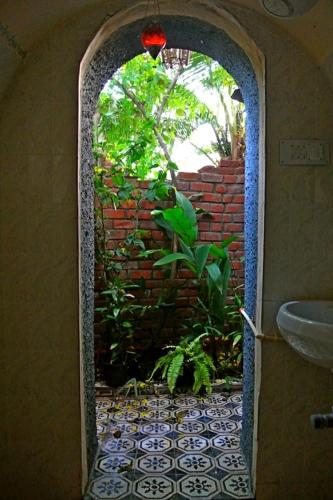 an open door to a bathroom with a brick wall at "Sunny Cow" Village Villa in Anjuna