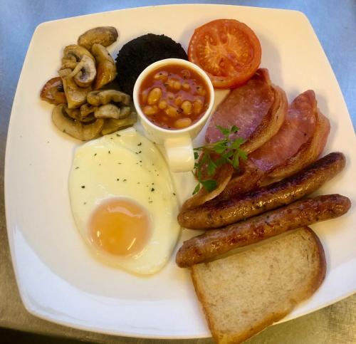 a plate of breakfast food with eggs bacon beans and mushrooms at Mariners Hotel in Seaton