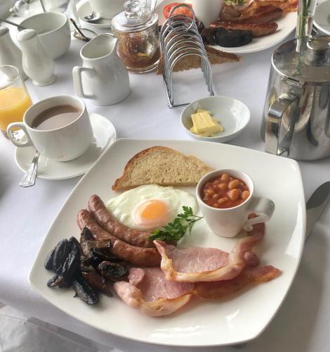 a plate of breakfast food with eggs bacon beans and toast at Mariners Hotel in Seaton