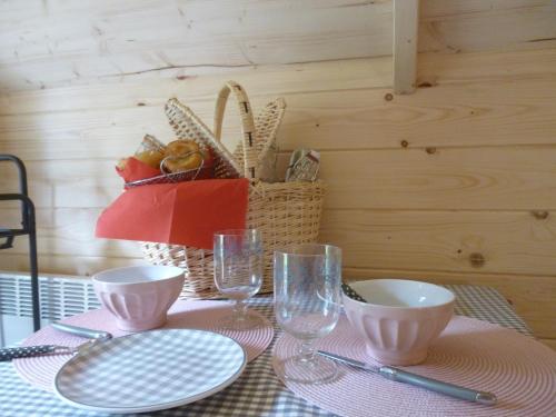 une table avec des assiettes, des verres et un panier dans l'établissement Les cabanes de Kerellou, à Plouigneau