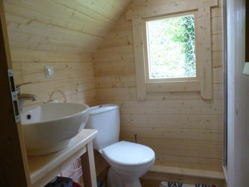 a bathroom with a toilet and a sink and a window at Les cabanes de Kerellou in Plouigneau