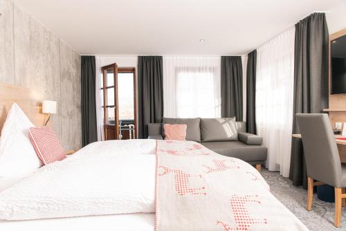 a bedroom with a large white bed and a couch at Genusshotel Hirschen - Erholung im Grünen (Südschwarzwald) in Sallneck