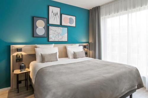 a bedroom with a large bed with blue walls at Appart'City Collection Genève Aéroport - Vernier in Geneva