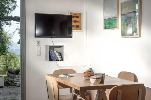a dining room table with chairs and a television on the wall at PaxosBlue Suites & Villas in Gaios