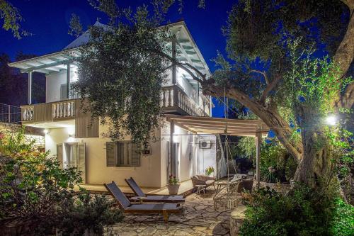 a house with chairs and a tree at night at PaxosBlue Suites & Villas in Gaios
