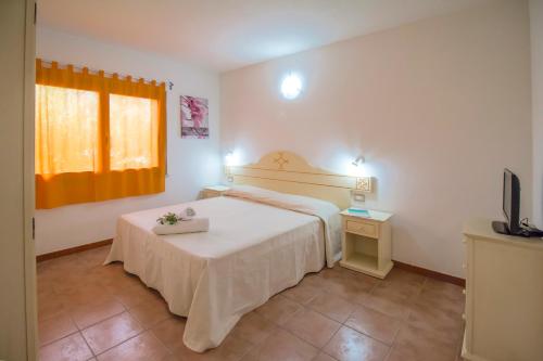 a bedroom with a white bed and a television at Rey beach Club in Monte Nai