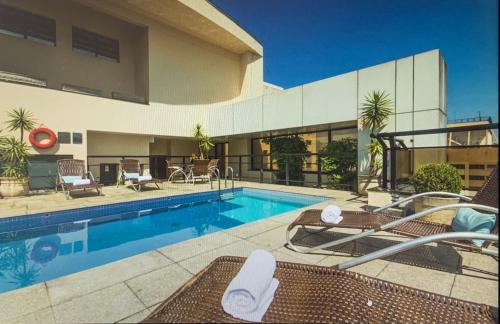 - une piscine avec des chaises à côté d'un bâtiment dans l'établissement Apart Alameda Lorena, à São Paulo