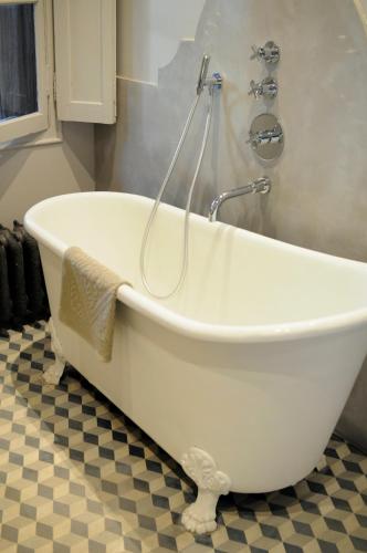 a white bath tub with a shower in a bathroom at La Divine Comédie-Suites Deluxe in Avignon