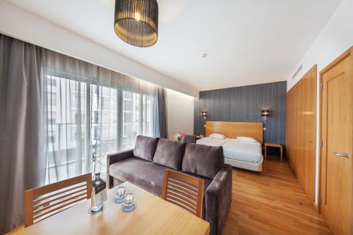 une chambre d'hôtel avec un canapé et un lit dans l'établissement Lux Fatima Park - Hotel, Suites & Residence, à Fátima