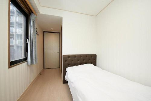 a white bed in a room next to a window at Hotel Empire in Shinjuku in Tokyo