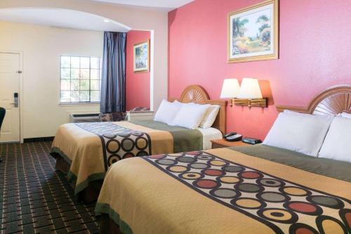 a hotel room with two beds and pink walls at Super 8 by Wyndham Stafford Sugarland Area in Stafford