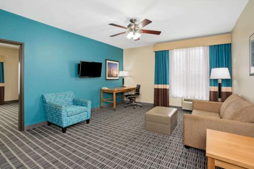 a living room with a couch and a chair and a desk at La Quinta by Wyndham Houston Willowbrook in Houston