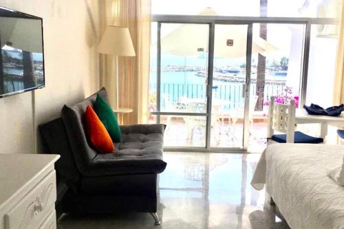 a bedroom with a chair and a bed and a balcony at Spectacular Hadas Sunset and Ocean view in Manzanillo