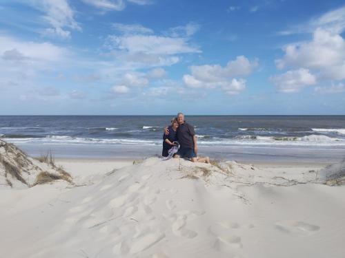 a man and woman sitting in the sand on the beach at Playa, bosque y lago in Montevideo