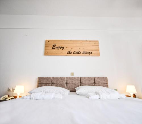 a bed with white sheets and a sign on the wall at Κastro Ηotel in Agios Kirykos