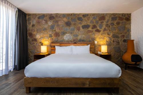 a bedroom with a large bed and two tables with lamps at Hotel Boutique Camino Del Bosque in Cholula