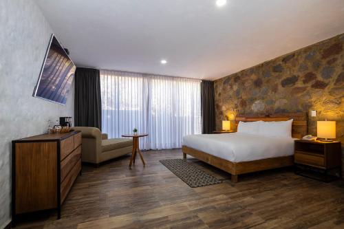 a hotel room with a large bed and a couch at Hotel Boutique Camino Del Bosque in Cholula
