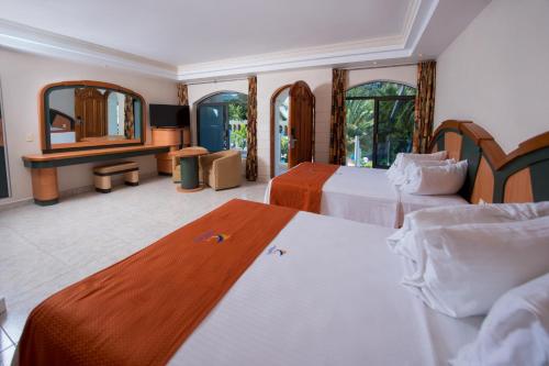 a hotel room with two beds and a mirror at Hotel Costa Azul in Acapulco