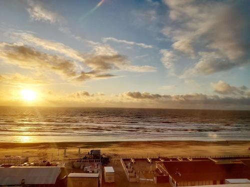a view of a beach with the sun setting over the ocean at Apartment Marmoris in Zandvoort
