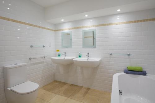 a bathroom with two sinks and a toilet and a tub at Beach View in St Ives