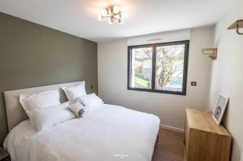 a bedroom with a white bed and a window at Chalet Hygge Saint Lary - gîtes de standing en coeur de village des Pyrénées in Saint-Lary-Soulan