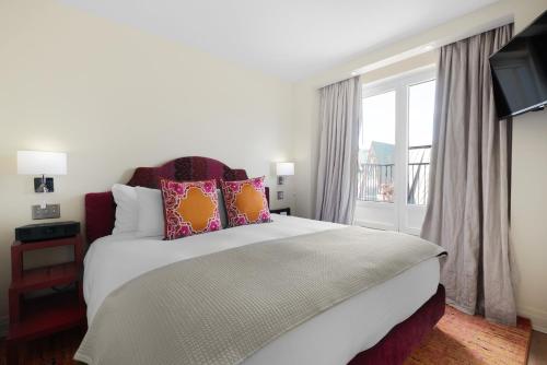 1 dormitorio con 1 cama grande con almohadas y ventana en Auberge Saint-Antoine, en Quebec