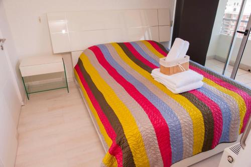 1 dormitorio con 1 cama con una manta a rayas de colores en Chilean Suites and Apartment, en Santiago