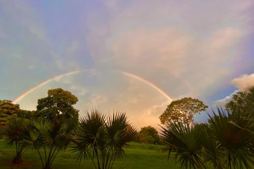 a rainbow in the sky over a field with trees at Estalagem Alter Real in Pirenópolis