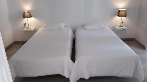 two beds in a room with white sheets and lamps at Hostel A Casa da Árvore in Faro