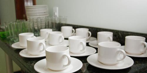 un grupo de tazas y platillos blancos en un mostrador en Imperial Hotel, en Santa Bárbara