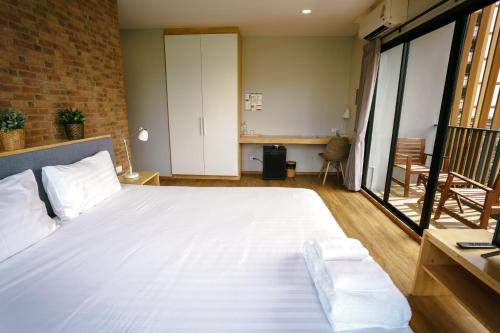 a bedroom with a large white bed and a balcony at Nest by Sangob in Bangkok