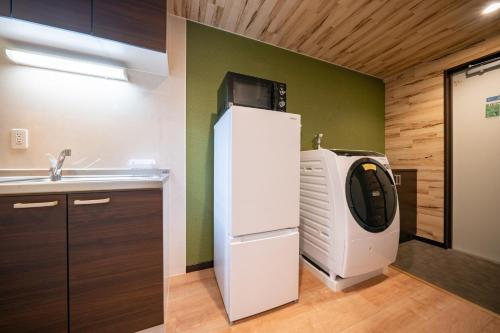 a kitchen with a white refrigerator and a sink at Residence Hotel Takayama Station in Takayama