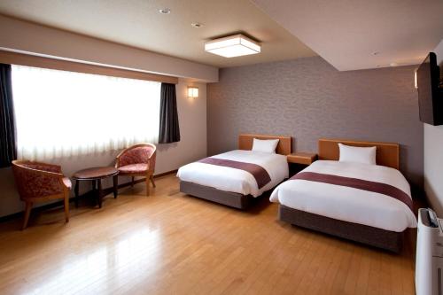 a hotel room with two beds and a window at Natural Hot Spring Yaoji Hakata Hotel in Fukuoka