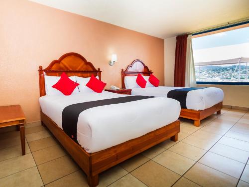 a hotel room with two beds and a window at Hotel De La Loma in Tlaxcala de Xicohténcatl