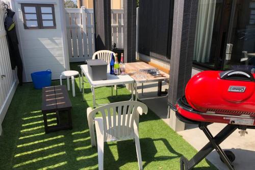 a patio with a table and chairs and a grill at KANRA ichinomiya in Ichinomiya