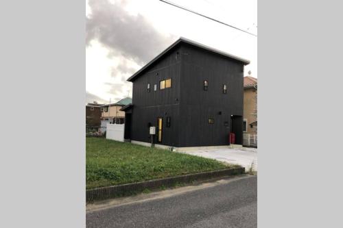 a black building with windows on the side of a street at KANRA ichinomiya in Ichinomiya