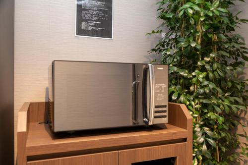 a microwave oven sitting on top of a wooden cabinet at Dormy Inn Premium Fukui Natural Hot Spring in Fukui