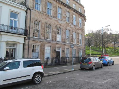 two cars parked in a parking lot in front of a building at Lantern Guest House in Edinburgh