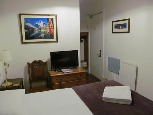 a bedroom with a bed and a television on a table at Lantern Guest House in Edinburgh