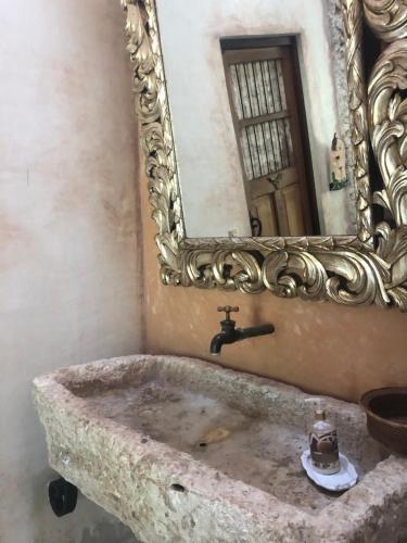 a bathroom with a stone sink with a mirror at Hacienda Sacnicte in Izamal