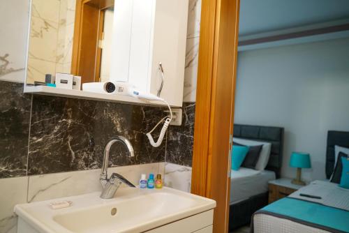 a bathroom with a sink and a mirror and a bed at YELKEN BEACH OTEL in Didim