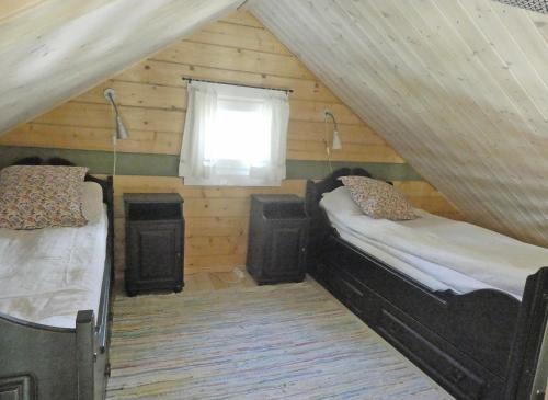 um quarto no sótão com 2 camas e uma janela em Fröya Timber Cottage em Arvika