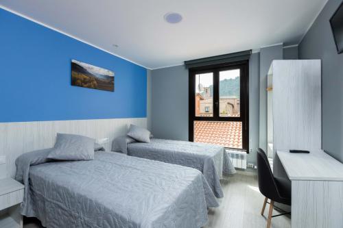 a bedroom with two beds and a desk and a window at Apartamentos Turísticos San Lorenzo in Nájera
