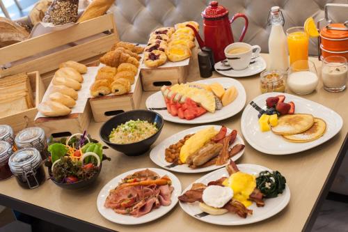 a table with plates of breakfast foods on it at ibis Styles Bangkok Silom in Bangkok