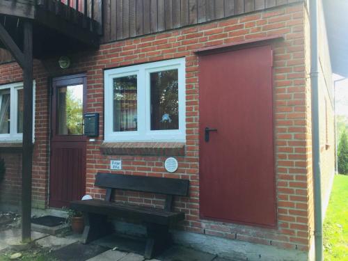 a brick building with a red door and a bench at Ferienwohnung Torge in Glücksburg