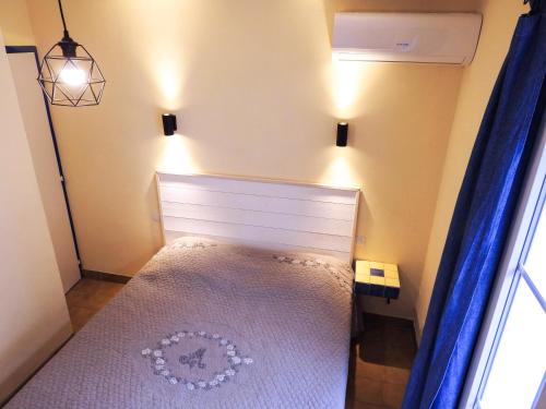 a small bedroom with a bed with blue curtains at La Villa Les Hespérides in Grimaud