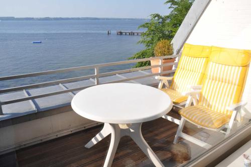 グリュックスブルクにあるFerienwohnung Strandkiekerの白いテーブル、水辺を見渡すバルコニー(椅子2脚付)