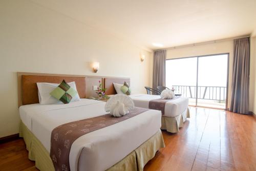 zwei Betten in einem Hotelzimmer mit großem Fenster in der Unterkunft New Travel Beach Hotel & Resort in Chao Lao Beach