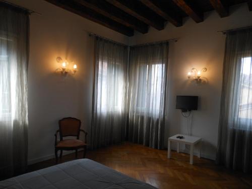 a bedroom with a bed and a chair and windows at Appartamenti A San Marco in Venice