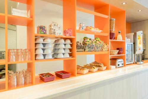 a display case in a bakery with orange shelves at Hôtel Eco La Rochelle Centre les Minimes in La Rochelle